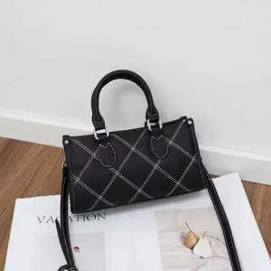 Black textured pillow shoulder bag with white contrast stitching and cross-body strap.