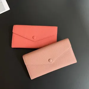 Detail view of two long genuine leather wallets in coral and pink with snap closure design.