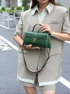Dark green leather crossbody bag with metal lock, elegant retro shoulder bag design.