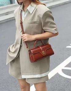 Detail view of retro brown cowhide leather crossbody bag with top handle and elegant hardware.