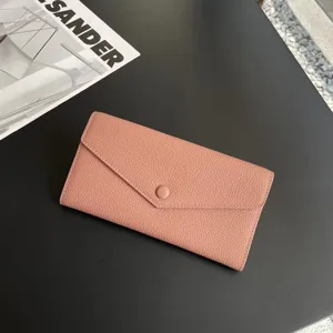 Pink leather long wallet detail showing soft pebble grain texture and snap button closure.