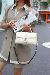 Detailed view of the vintage white leather top-handle crossbody bag with metal lock.