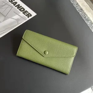 Green pebbled leather long wallet detail, sleek envelope design with snap button closure.