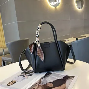 Vista detallada de bolso de piel negra con pañuelo estampado elegante en el asa.