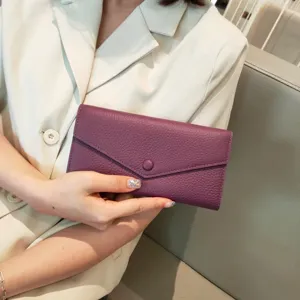 Close-up view of the purple leather long envelope wallet held by hand, showing soft texture.