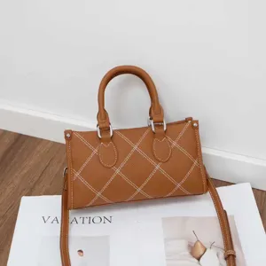 Details of the brown leather pillow shoulder bag featuring stylish cross stitching and handles.