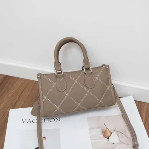 Detail view of stylish minimalist taupe shoulder pillow bag with contrast white stitching.