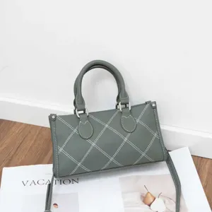 Detail shot of the gray-green stylish shoulder crossbody pillow bag with white contrast stitching.
