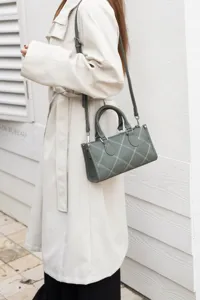 Minimalist green shoulder bag for women with contrast white stitching and chic design.
