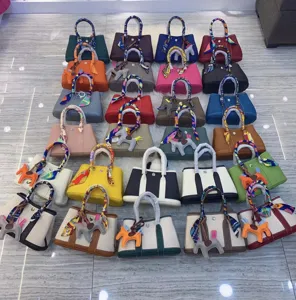 Vista dettagliata di varie borse tote in pelle alla moda con foulard in seta e ciondoli.