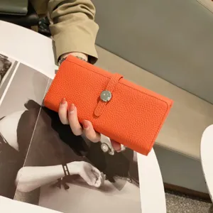 Orange pebbled leather long wallet for women with metal snap button and stylish strap design.