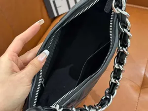 Close-up detail of black quilted leather shoulder bag interior, metal chain strap view.
