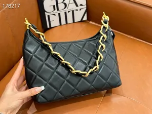 Black quilted leather underarm shoulder bag with chunky gold chain strap for women.