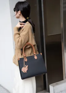 Dettaglio borsa shopper in vera pelle da donna, borsa a mano nera e marrone con ciondolo.