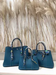 Borsa tote in pelle blu con manico avvolto in foulard di seta, elegante shopper minimalista.