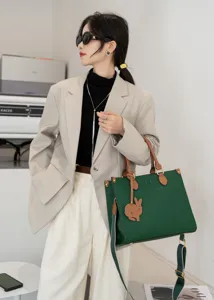 Vista dettagliata della grande borsa tote in vera pelle verde con manici marroni.