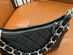 Black quilted leather underarm bag close-up showing luxury chain strap and smooth zipper detail.