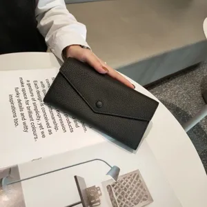 Close-up detail of black genuine leather long envelope wallet featuring classic pebble grain texture.