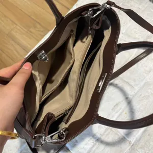 Dark brown leather tote bag interior detail view with multi-compartment design and metal hardware.