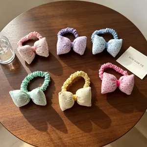 Vue détaillée d'élastiques à cheveux à nœud pois colorés sur table en bois, tissu doux.