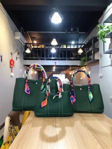 Vista dettagliata delle borse tote in pelle verde con foulard colorati sul tavolo espositivo.