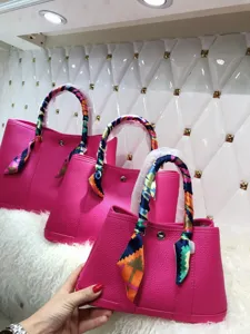 Borsa a mano elegante in vera pelle rosa con foulard colorato sui manici da donna.