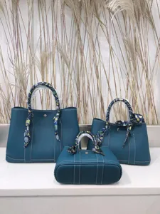 Dettaglio della borsa shopper in pelle blu stile giardino con foulard sul manico.