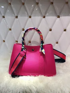 Vista dettagliata della borsa in pelle rosa, con foulard twilly colorato e tracolla sportiva.