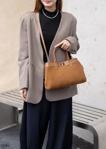 Detailed view of the contrast suede tote bag featuring top handle and metal lock closure.