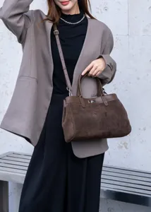 Detailed close-up view of dark brown suede tote bag featuring top handle and metal lock.