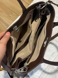 Dark brown leather tote bag with multi-compartment interior, zipper pockets and metal hardware.