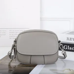 Dettaglio borsa a tracolla in pelle grigia con cuciture fini, hardware argentato e forma a mela.