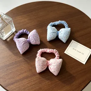 Gros plan de charmants chouchous à pois en tissu rose, bleu et violet pour cheveux.