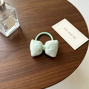 Gros plan détaillé d'un joli chouchou nœud vert clair à pois posé sur une table en bois.
