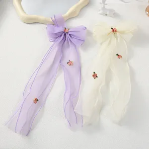 Nahaufnahme von Organza Schleifen Haarspangen in Lila und Beige mit Rosenstickerei für Mädchen.