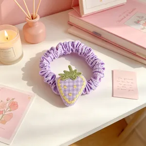 Coletero de pelo de fresa a cuadros morados, detalle de accesorio de estilo dulce.