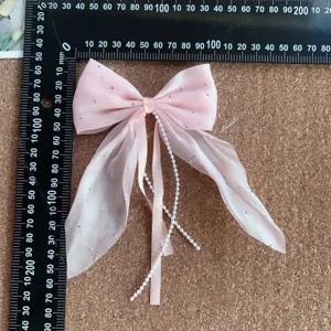 Detail view of pink bow hair clip with pearl chains and sparkling details for cute daily hairstyles.