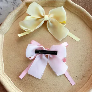 Sweet bow hair clip with ribbons, cute girls hair accessory, detail shot on tray.