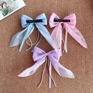 Detailed shot of sweet bow hair clips with pearl tassels in blue pink and purple for girls.
