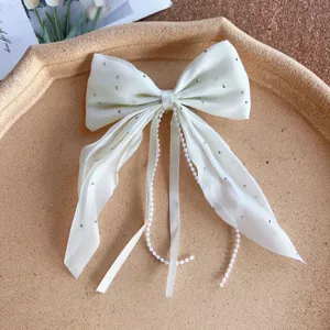 White bow hair clip with sparkling rhinestones and delicate pearl tassel chains for women.