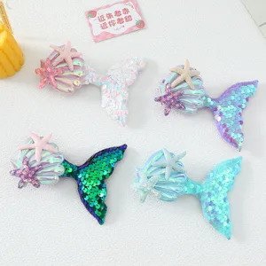 Close-up details of sparkly mermaid tail hair clips with seashell and starfish accents.