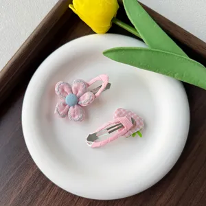 Gros plan des détails de jolies pinces à cheveux roses en tissu fleur et fraise pour les enfants.