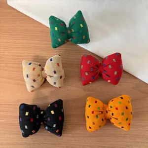 Fabric bow hair ties detail view featuring colorful square patterns in five vibrant shades.