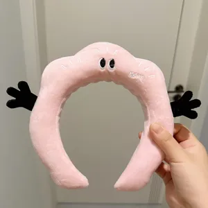 Vue détaillée du cerceau à cheveux en peluche, bandeau dessin animé rose pour le soin du visage.