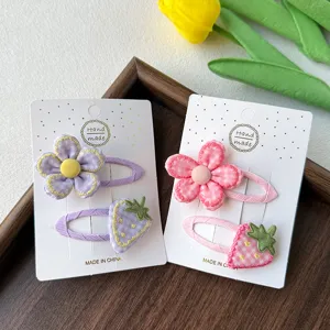 Vue détaillée de pinces à cheveux mignonnes en tissu fleur et fraise, accessoires pour enfants.