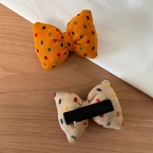 Detail view of fabric bow hair clips with colorful square pattern, chic daily hair accessory.