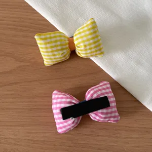 Gros plan détaillé de pinces à cheveux à nœud en tissu vichy jaune et rose, style mignon.