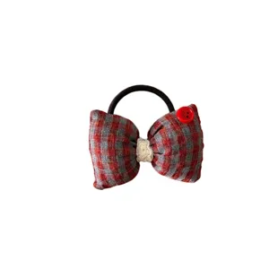Dettaglio elastico capelli a fiocco a quadri rosso grigio, fermaglio in tessuto imbottito.