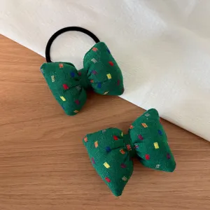 Green fabric bow hair tie detail, showing the colorful woven texture and black elastic rubber band.
