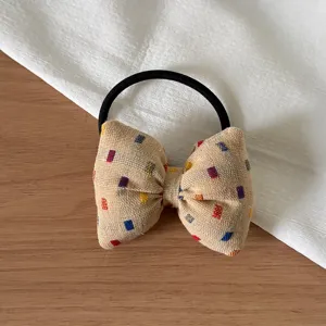Detailed view of a cute Korean style bow hair tie with colorful woven pattern and black elastic band.